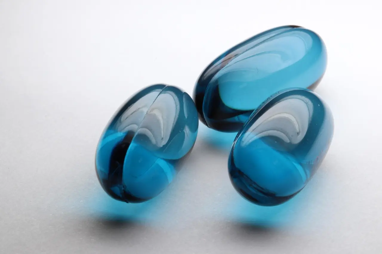Three blue glass beads, indicative of medicine, displayed on a white surface.